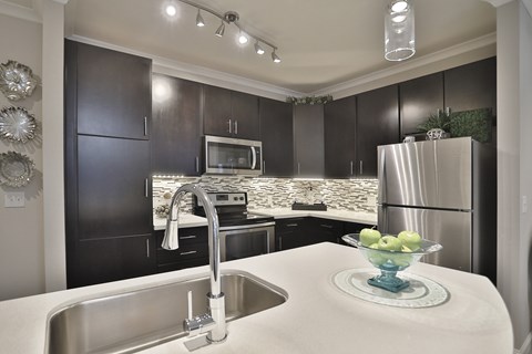 A modern kitchen with a stainless steel refrigerator and a white countertop.