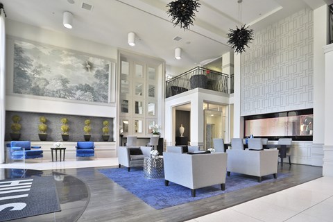 A spacious lobby with a blue rug and white furniture.