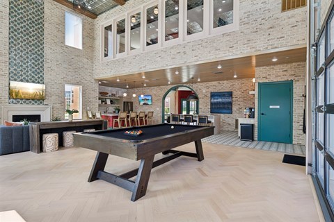 A pool table in the resident lounge with a brick wall and a fireplace.