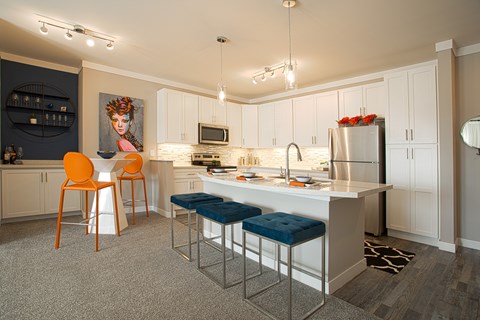 A kitchen with a white counter top and blue stools.