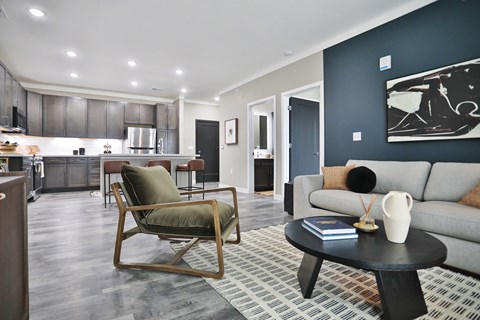 A modern living room with a grey couch and a wooden rocking chair.