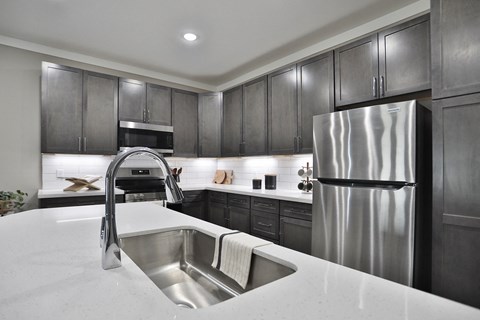 A modern kitchen with a stainless steel refrigerator and a marble countertop.