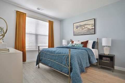 a bedroom with a bed and a window with orange curtains