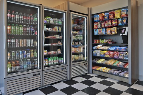 A row of refrigerators filled with drinks and snacks.