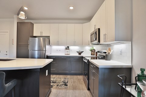 A modern kitchen with a refrigerator, microwave, and oven.