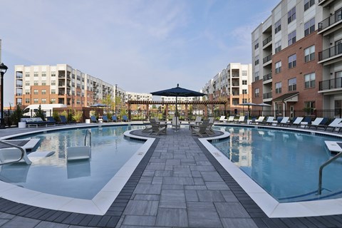 A large outdoor pool surrounded by lounge chairs and umbrellas.