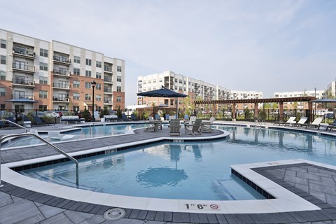 A large outdoor pool surrounded by buildings and lounge chairs.