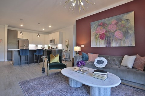 A living room with a grey couch, a coffee table, and a painting on the wall.