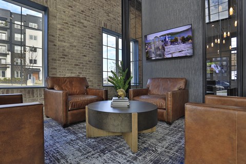 a lobby with brown leather chairs and a table with a plant