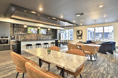a dining room with tables and chairs and a kitchen with a bar
