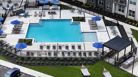 A large outdoor swimming pool surrounded by lounge chairs and umbrellas.