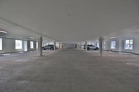 A large, empty parking garage with two cars parked in it.