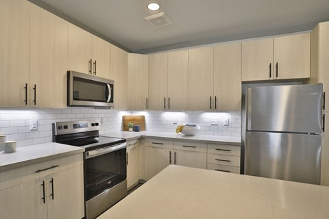a kitchen with white counter tops and stainless steel appliances