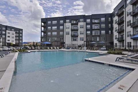 A large swimming pool in front of apartment buildings.