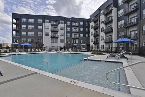 A large swimming pool in front of apartment buildings.