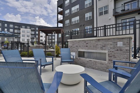A patio with blue chairs and a fireplace.