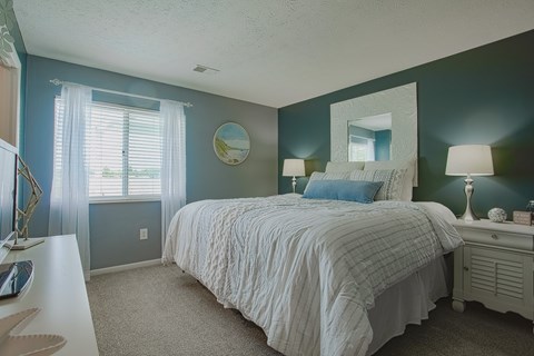 A bedroom with a bed, nightstand, and window.