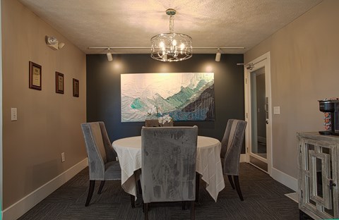 A dining room with a table set for two and a painting on the wall.
