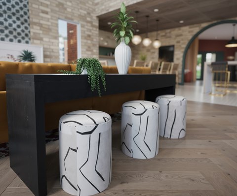 A plant sits on a black table with three white stool with black lines.