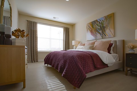 A bedroom with a bed covered in a purple comforter.