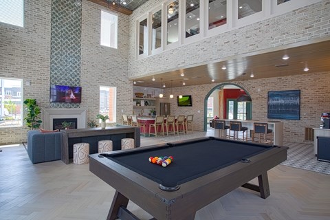 A pool table is in the middle of a room with a brick wall.
