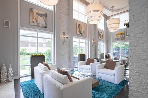 A living room with white furniture and a blue rug.