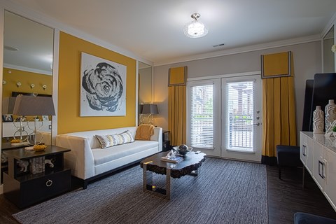 A living room with a white couch and a painting on the wall.
