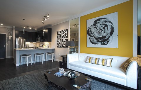 A modern living room with a white couch and a large abstract painting on the wall.