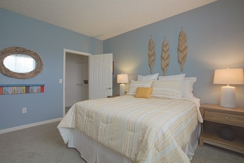 A bedroom with a bed, nightstand, and a mirror on the wall.