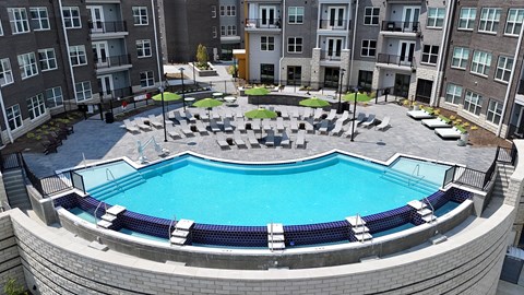 A round swimming pool surrounded by a stone patio and lounge chairs.