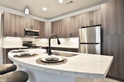 A modern kitchen with a white countertop and stainless steel appliances.