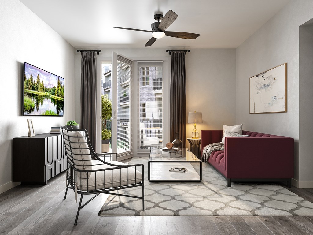 a living room with a red couch and a chair and a ceiling fan