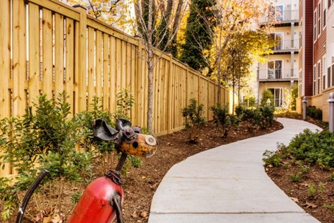 A red fire hydrant sits on a sidewalk in a garden.