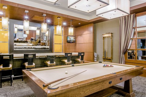 A pool table in a room with a mirror and a TV.