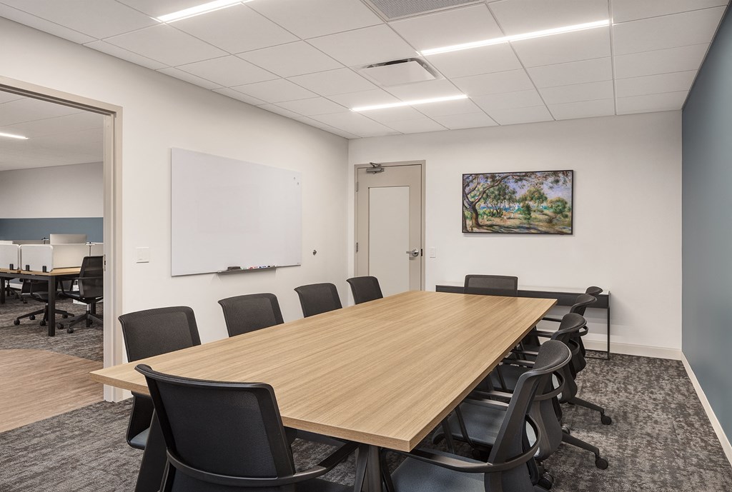 a conference room with a wooden table and black chairs