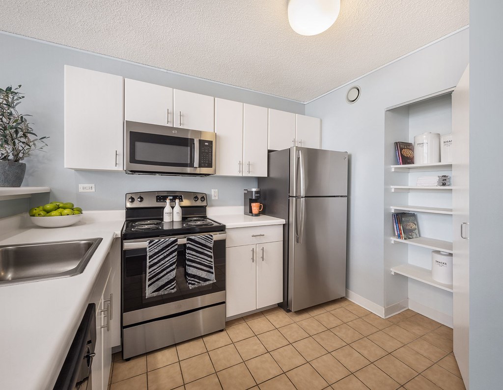 A kitchen with a stove, refrigerator, and microwave.
