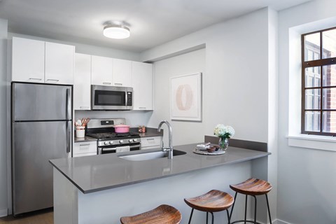 A modern kitchen with a stainless steel refrigerator, microwave, and a sink with a faucet.