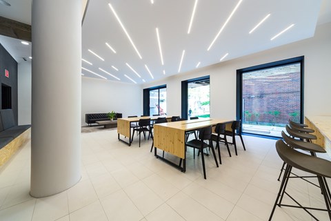 A room with tables and chairs and a long white column.