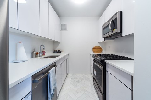A modern kitchen with white cabinets and a black stove top oven.