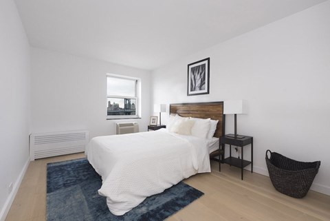 A bedroom with a white bed and a window.