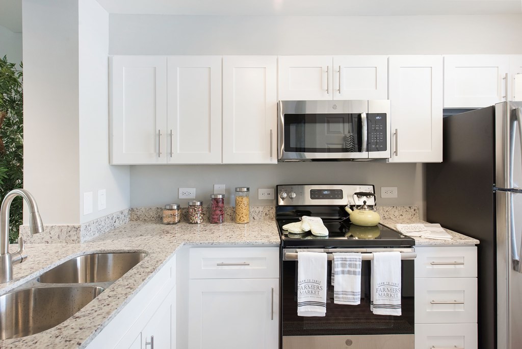 A kitchen with white cabinets and a black refrigerator.