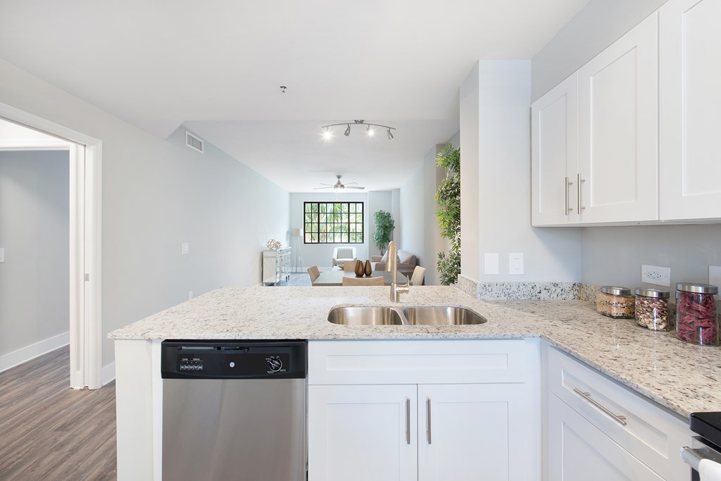 A kitchen with white cabinets and a granite countertop.