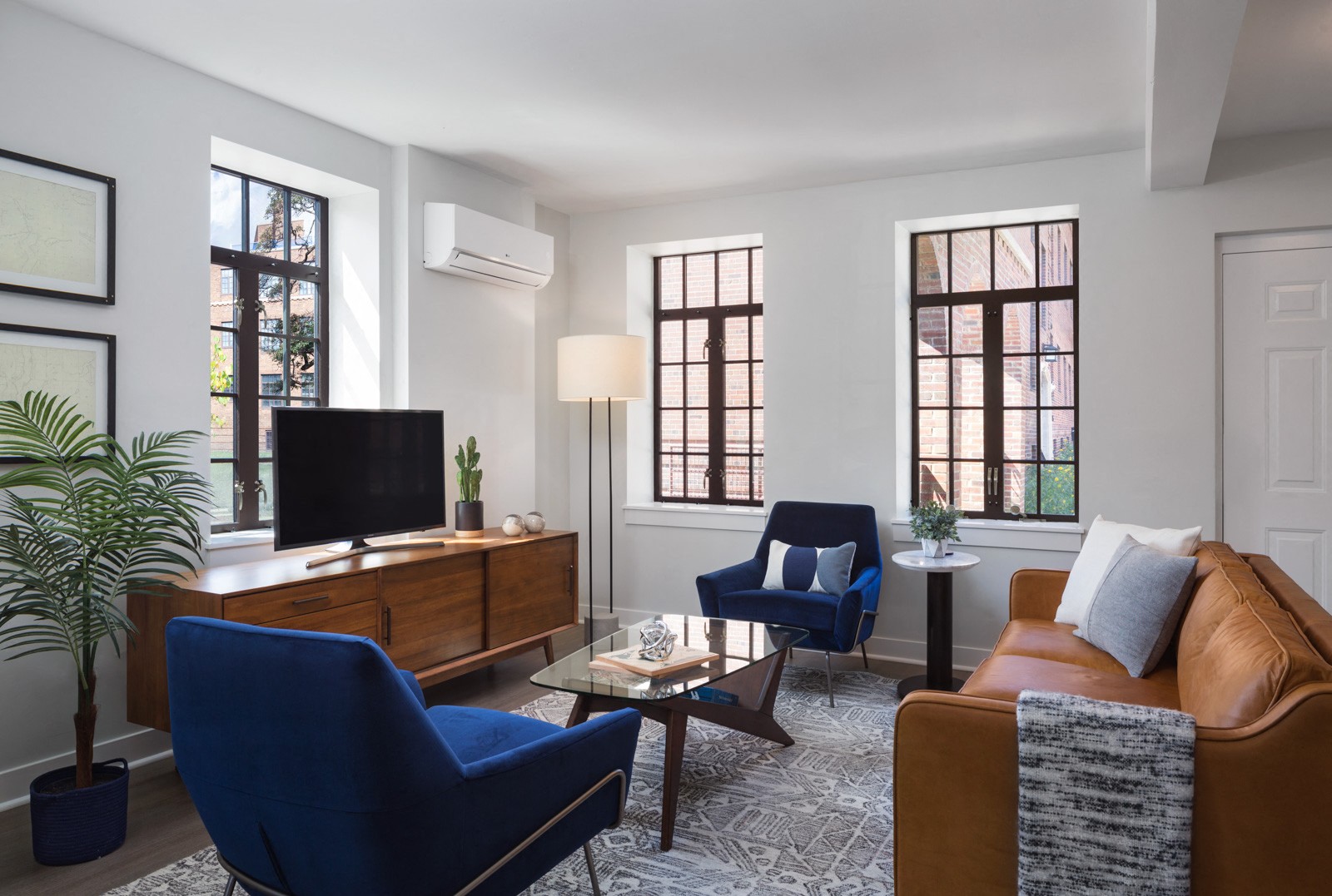 A living room with a blue chair, a brown couch, and a wooden cabinet.