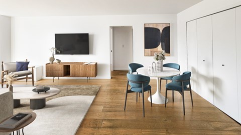 A modern living room with a white table and blue chairs.