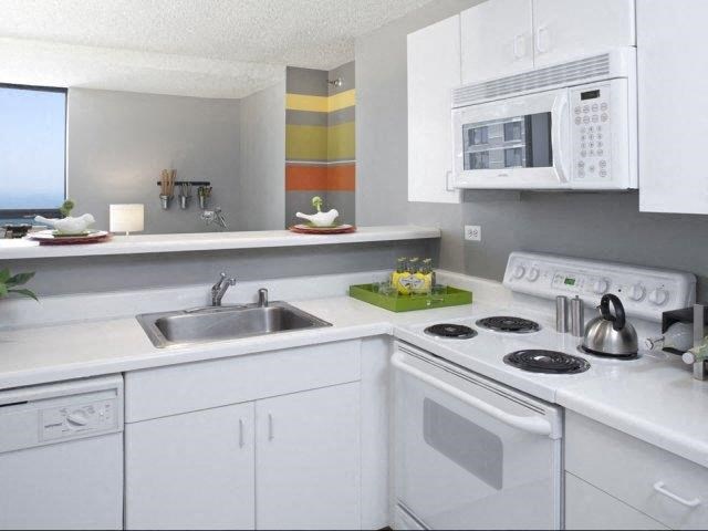 a white kitchen with a stove microwave and sink