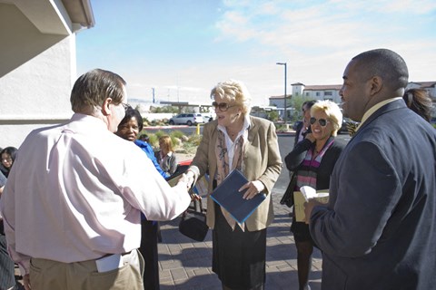 a group of people standing around a man shaking hands