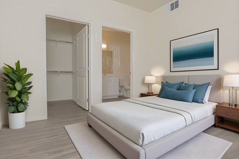 A bedroom with a large bed and a potted plant.