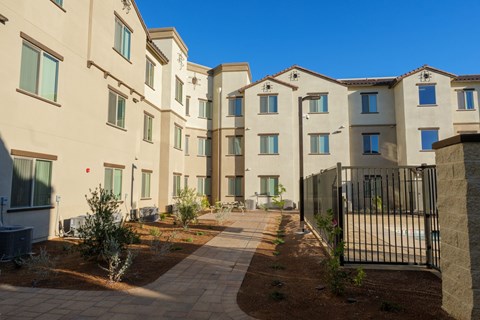 A row of modern apartment buildings with a black fence in the foreground.