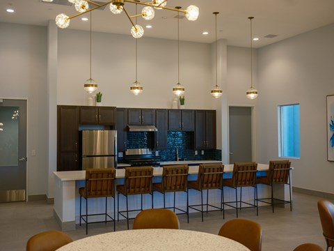 A modern kitchen with a bar area and chairs around it.