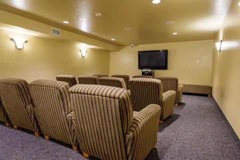 A row of striped chairs are arranged in front of a television in a room.